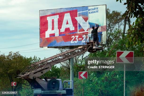 Man glues a referendum poster reading "Yes" in Berdyansk on September 26, 2022. - Western nations dismissed the referendums in Kremlin-controlled...