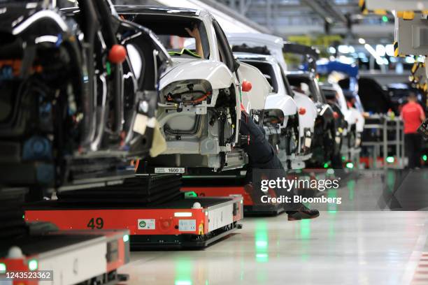 Employees work on the body shells of all-electric Porsche Taycan luxury automobiles on the production line at the Porsche AG factory in Stuttgart,...