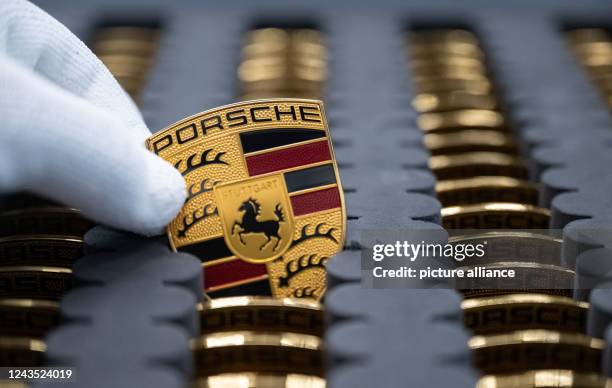 September 2022, Baden-Wuerttemberg, Stuttgart: A Porsche AG employee shows the Porsche logo in a production hall at Porsche's main plant. The...