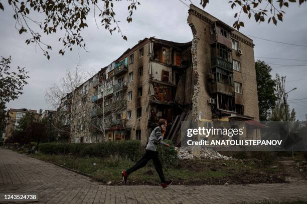 Man runs in front of a destroyed apartment building in Bakhmut, Donetsk region on September 26 amid Russia's invasion of Ukraine.