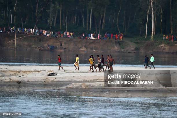 Graphic content / People carry the dead body of a victim who died after a boat capsized in river Karotoa near Boda town on September 26, 2022. -...