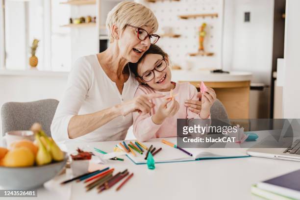 großmutter und enkelin spielen am tisch - origami spiel stock-fotos und bilder