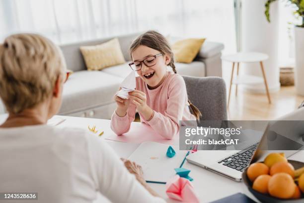 grandmother and granddaughter playing at the table - origami instructions stock pictures, royalty-free photos & images