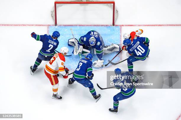 Vancouver Canucks goaltender Arturs Silovs makes a save as defenseman Luke Schenn defenseman Jack Rathbone left wing Phillip Di Giuseppe and center...