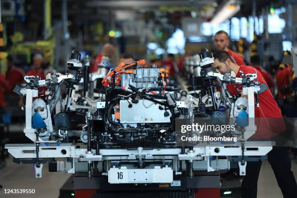 Employees work on the chassis of all-electric Porsche Taycan luxury automobiles on the production line at the Porsche AG factory in Stuttgart,...