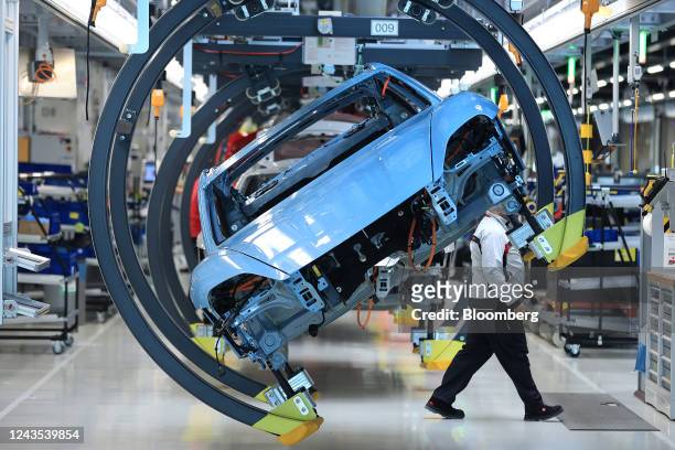 The body shell of an all-electric Porsche Taycan luxury automobile in an overhead conveyor cradle on the production line at the Porsche AG factory in...