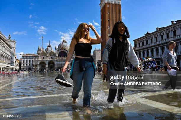 Tourists walk across a flooded St. Mark's square in Venice on September 27 following an "Alta Acqua" high tide event, too low to operate the MOSE...