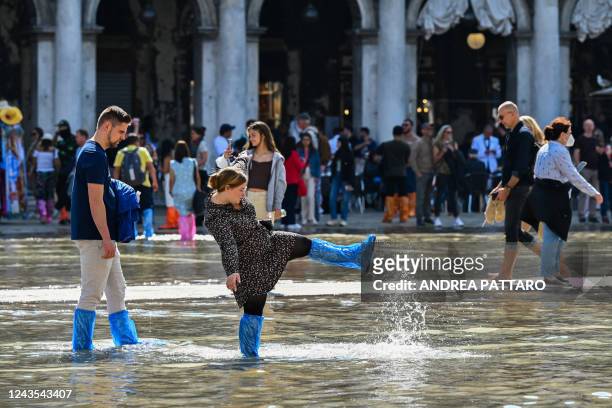 Tourists wearing walk across a flooded St. Mark's square in Venice on September 27 following an "Alta Acqua" high tide event, too low to operate the...