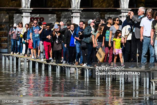 Tourists walk across an elevated walkway at St. Mark's square in Venice on September 27 following an "Alta Acqua" high tide event, too low to operate...