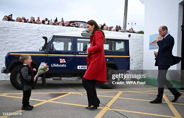 Prince William, Prince of Wales looks on as his wife Catherine, Princess of Wales is presented with a posy of flowers by four-year-old Theo Crompton...