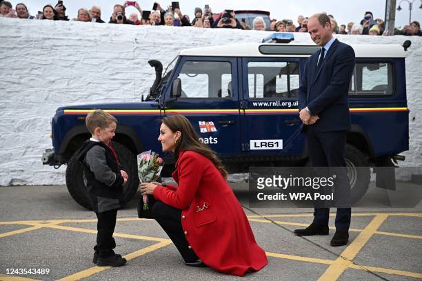Prince William, Prince of Wales looks on as his wife Catherine, Princess of Wales is presented with a posy of flowers by four-year-old Theo Crompton...