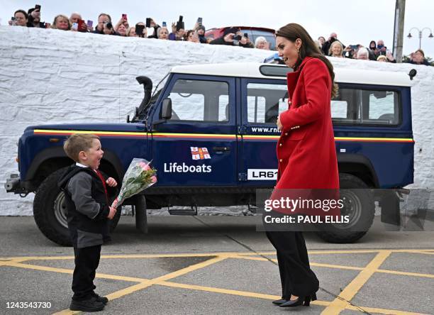 Britain's Catherine, Princess of Wales reacts as she is presented with a posy of flowers by four-year-old Theo Crompton during a visit to the RNLI...