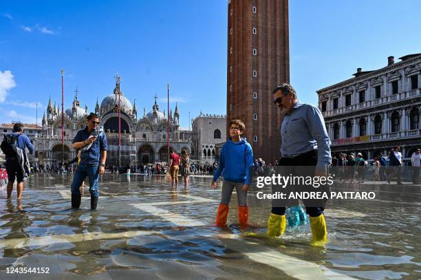 Tourists wearing waterproof plastic shoe covers walk across a flooded St. Mark's square in Venice on September 27 following an "Alta Acqua" high tide...