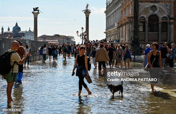 Tourists take photos on a flooded St. Mark's square by St. Mark's basilica in Venice on September 27 following an "Alta Acqua" high tide event, too...