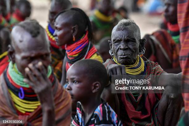 Women from the pastoral Turkana community and their children wait in a cluster in the shadow of a tree during an integrated outreach provided at a...