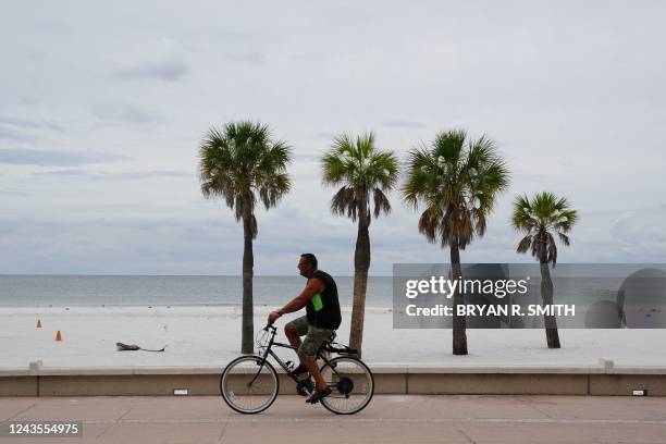 Man rides a bike along Clearwater Beach ahead of Hurricane Ian on September 27, 2022 in Clearwater. - The US National Hurricane Center said Ian made...