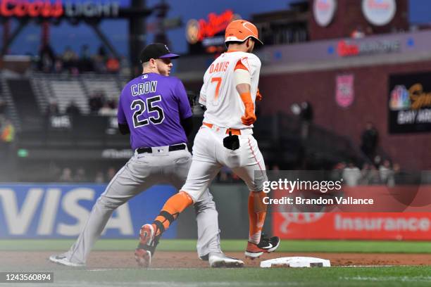 Cron of the Colorado Rockies errors on a ball thrown to him as J.D. Davis of the San Francisco Giants lands on first base in the first inning against...