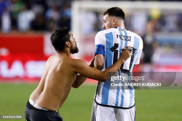 Argentina's Lionel Messi reacts to a fan who ran onto the pitch to ask for an autograph during the international friendly football match between...