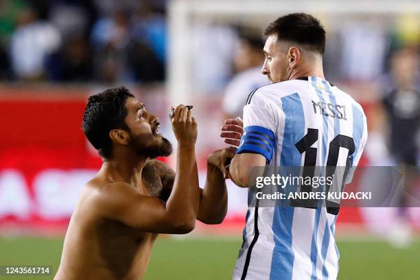 Argentina's Lionel Messi reacts as a fan ran on the pitch to ask for his autograh during the international friendly football match between Argentina...