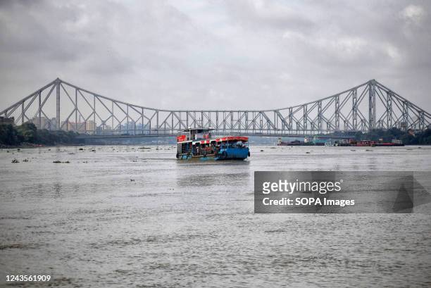 Passenger vessel seen on the River Ganges crossing the famous Howrah Bridge of kolkata.