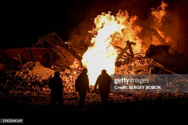 Ukrainian Firefighters stand in front of flames as a fire erupted at a depot of the freight railway station in Kharkiv, which was partially destroyed...