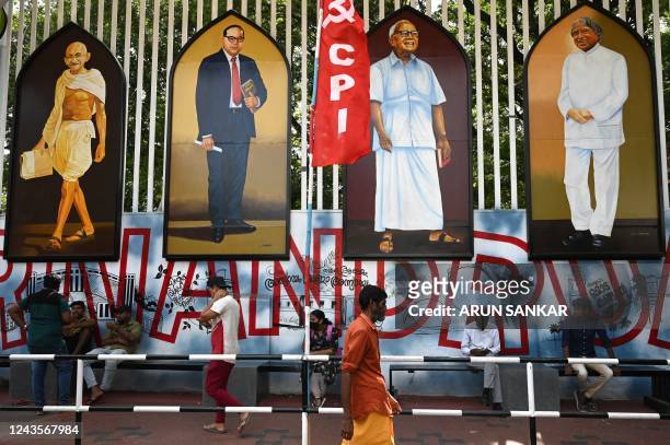 People wait for transportation next to paintings of Indian independence icon Mahatma Gandhi, father of Indian constitution BR Ambedkar, former chief...