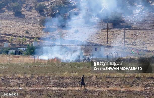 Kurdish peshmerga fighter walks as smoke billows in the area of Zargwez, 15 kms outside the Iraqi city of Sulaimaniyah, where several exiled...