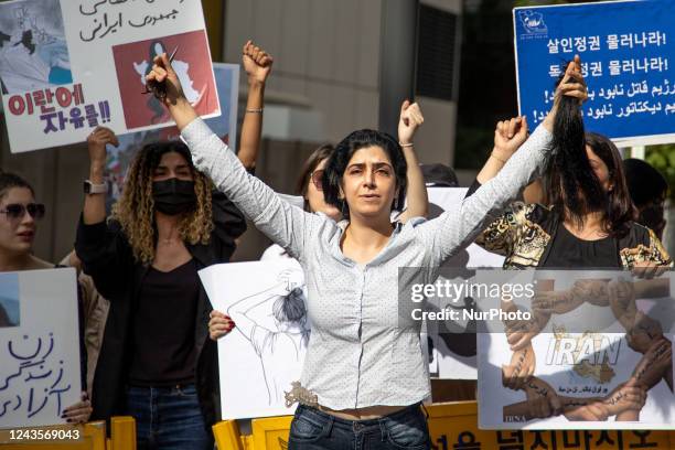 Member of the Iranian community in Seoul shout slogans after cuts her hair outside the Embassy of the Islamic Republic of Iran during a rally to...