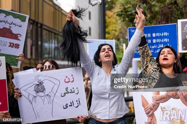 Member of the Iranian community in Seoul shout slogans after cuts her hair outside the Embassy of the Islamic Republic of Iran during a rally to...