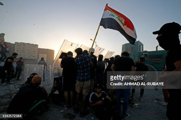Supporters of Shiite Muslim cleric Moqtada Sadr take cover amid clashes with Iraqi security forces in Tahrir Square in the centre of Iraq's capital...