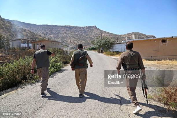 Kurdish peshmerga fighters walk to inspect the damage following an Iranian cross-border attack in the area of Zargwez, where several exiled left-wing...