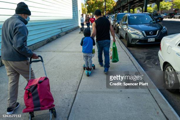 Child joins his father as residents receive food at the St. Helena Pantry in the Bronx on September 28, 2022 in New York City. The weekly pantry...