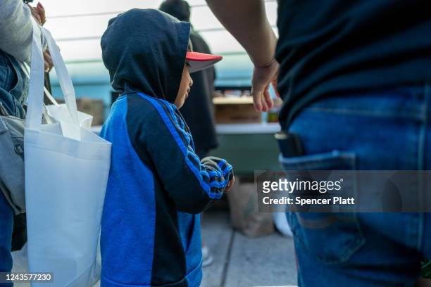 Child joins his father as Bronx residents receive food at the St. Helena Pantry in the Bronx on September 28, 2022 in New York City. The weekly...