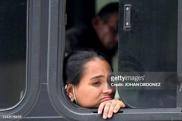 Woman part of a group of 81 migrants from Venezuela, Cuba, Haiti, Senegal, and Ghana sits on a bus after being detained by security forces and...