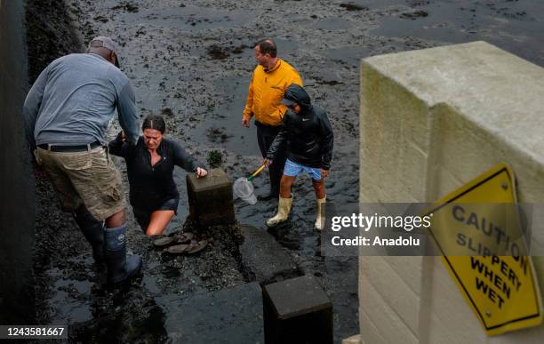 Woman gets help climbing from a muddy area in Tampa, Florida, United States on September 28, 2022. Hurricane Ian made landfall on Wednesday near...