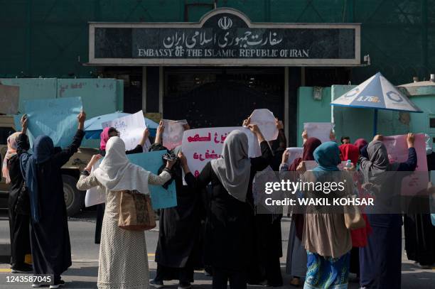 Afghan women hold placards as they take part in a protest in front of the Iranian embassy in Kabul on September 29, 2022. Taliban forces fired shots...