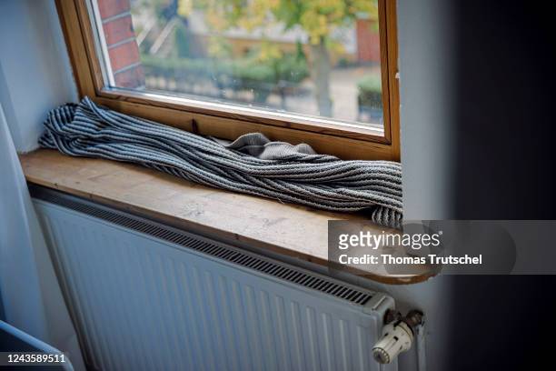 Symbolic photo on the subject of cold apartments. A blanket lies on the window sill in front of a poorly insulated window to protect against cold air...