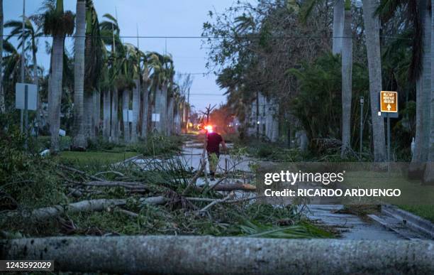 Man walks through debris on a street in the aftermath of Hurricane Ian in Punta Gorda, Florida on September 29, 2022. - Hurricane Ian left much of...