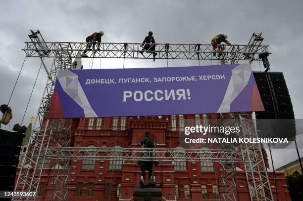 Workers fix a banner reading "Donetsk, Lugansk, Zaporizhzhia, Kherson - Russia!" on top of a construction installed in front of the State Historical...