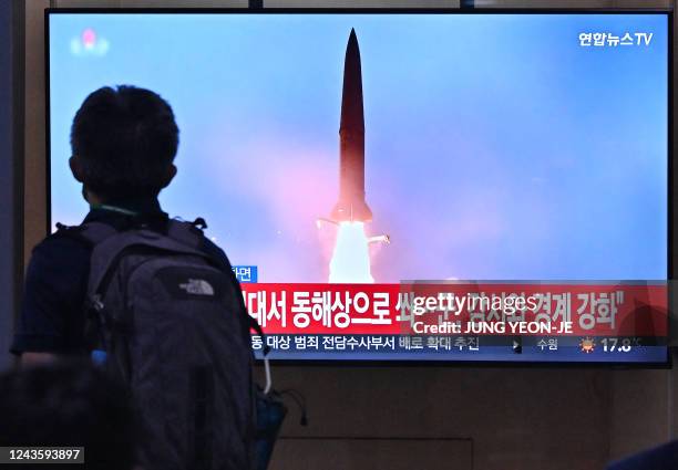 Man walks past a television screen showing a news broadcast with file footage of a North Korean missile test, at a railway station in Seoul on...