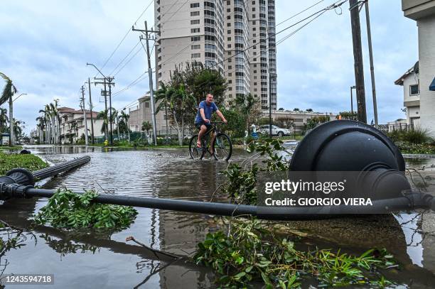 Man cycles through water past a downed street lamp in the aftermath of Hurricane Ian in Fort Myers, Florida, on September 29, 2022. - Hurricane Ian...