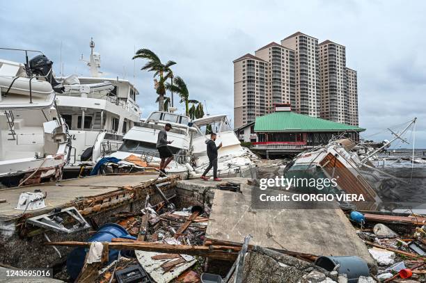 Residents inspect damage to a marina as boats are partially submerged in the aftermath of Hurricane Ian in Fort Myers, Florida, on September 29,...