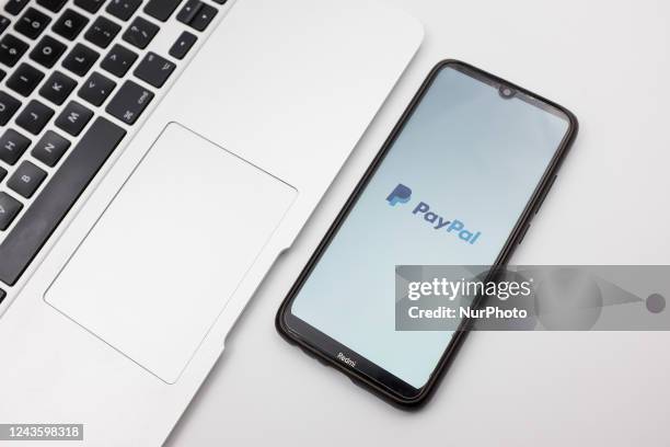 In this photo illustration a PayPal logo seen displayed on a smartphone screen on a desk next to a Macbook in Athens, Greece on September 29, 2022.