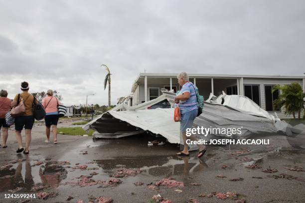 People walk past debris from a mobile home park in Fort Myers, Florida, on September 29 one day after Hurricane Ian made landfall. - Hurricane Ian...