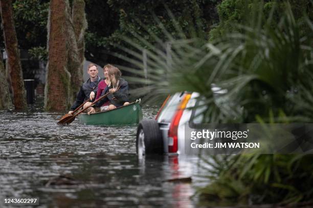 People paddle by in a canoe next to a submerged car in the aftermath of Hurricane Ian in Orlando, Florida on September 29, 2022. - Hurricane Ian left...