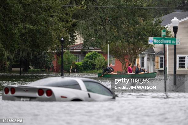People paddle by in a canoe next to a submerged Chevy Corvette in the aftermath of Hurricane Ian in Orlando, Florida on September 29, 2022. -...