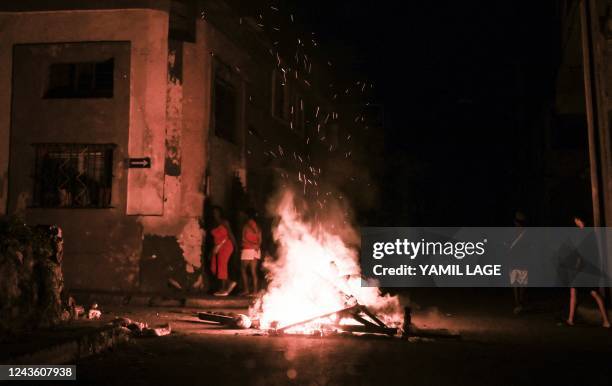 People walk by a bonfire set in the middle of a street during a power outage in Havana, September 29, 2022. Ian had plunged all of Cuba into darkness...