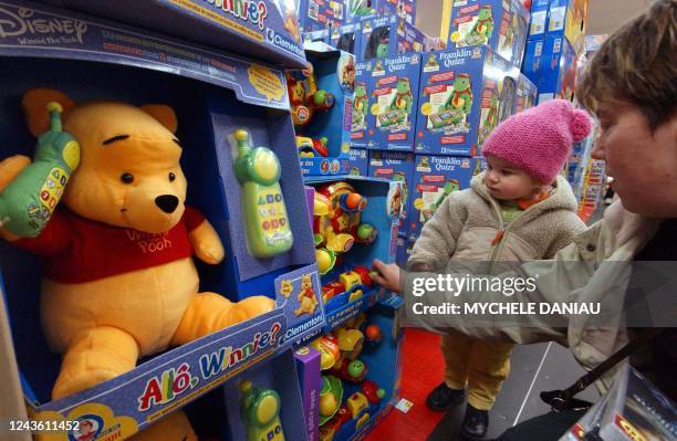 Un enfant regarde des peluches avec sa mère, le 25 novembre 2004 dans une grande surface de Rots , un mois avant la fête de Noël. AFP PHOTO MYCHELE...