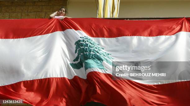 Girl looks outside the balcony of her house decorated with a huge Lebanese flag in Beirut, 13 April 2005. Lebanon sought to promote unity as it...