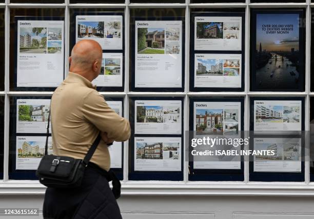 Member of the public looks at residential properties displayed for sale in the window of an estate agents' in London on September 30, 2022.